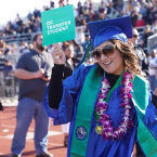 Oxnard College graduate holding a sign that reads: OC Transf