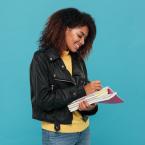 African American woman smiling while highlighting in a textbook.