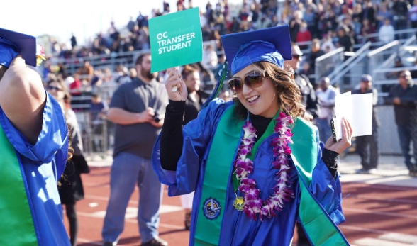 Oxnard College graduate holding a sign that reads: OC Transf