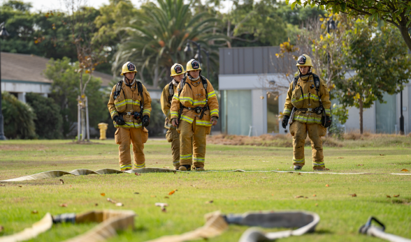 Four Fire Academy students standing outdoors in uniforms wit