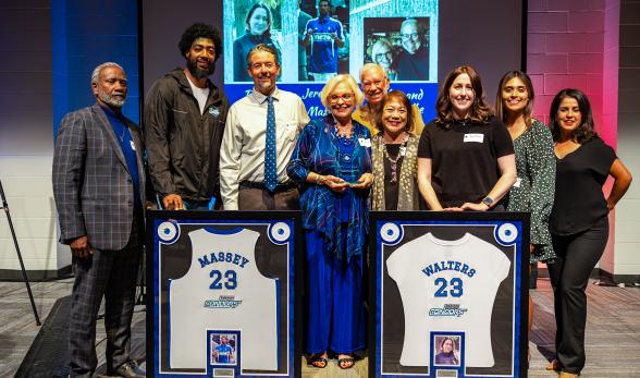 A group of nine people smiling for a photo at a jersey retir