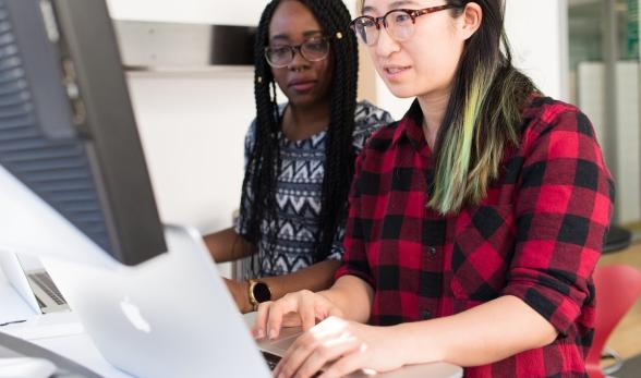 Two women sharing a computer screen.